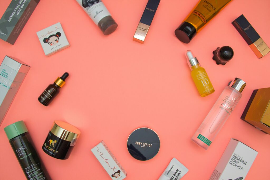 Top view of various cosmetic products for skincare and beauty in different bottles placed on pink surface